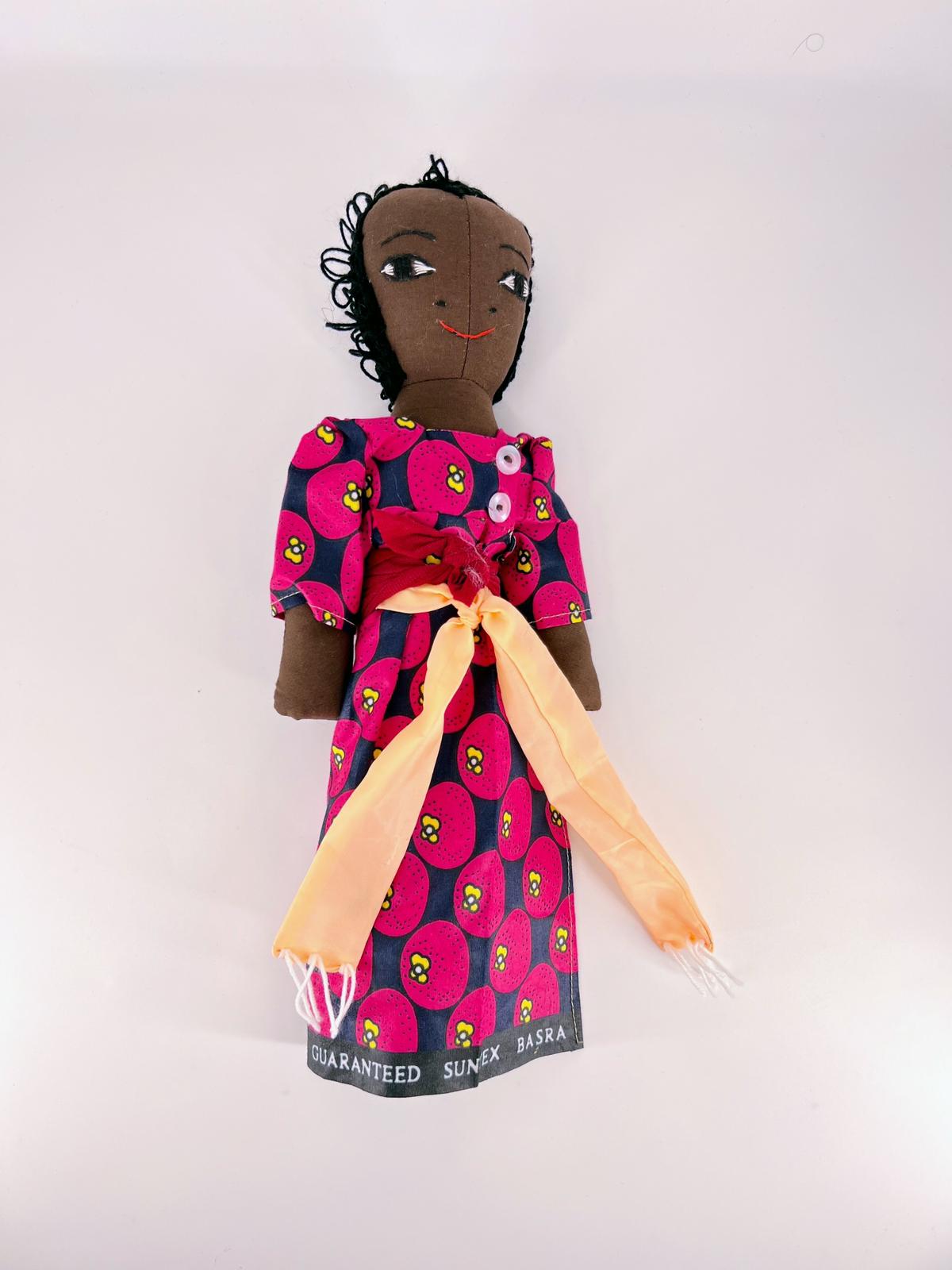 African Doll wearing a gomesi dress